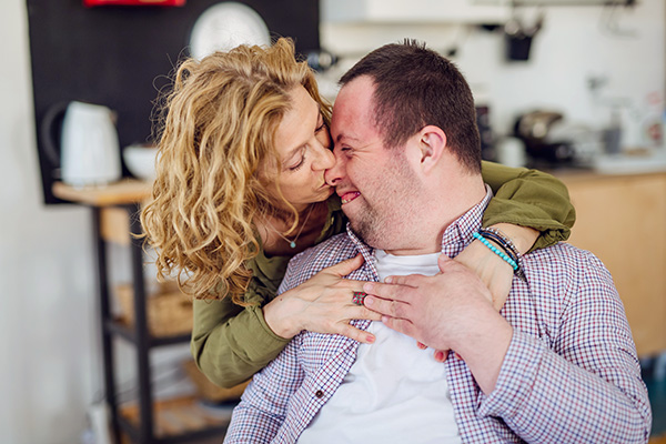 A portrait of mother hugging her grown up son with Down syndrome,