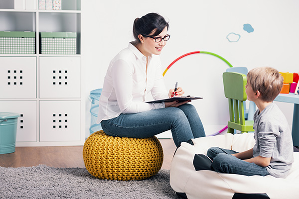 Smiling psychologist talking with kid during meeting in the classroom