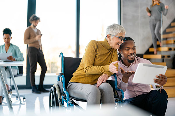 a business woman in a wheelchair talking to a businessman