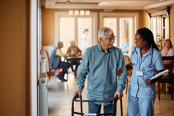 a nurse walking an elderly man holding a walker