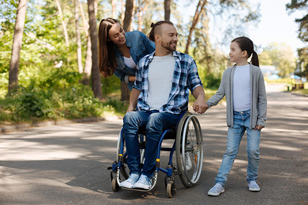 A dad in a wheelchair with his wife and daughter on a walk