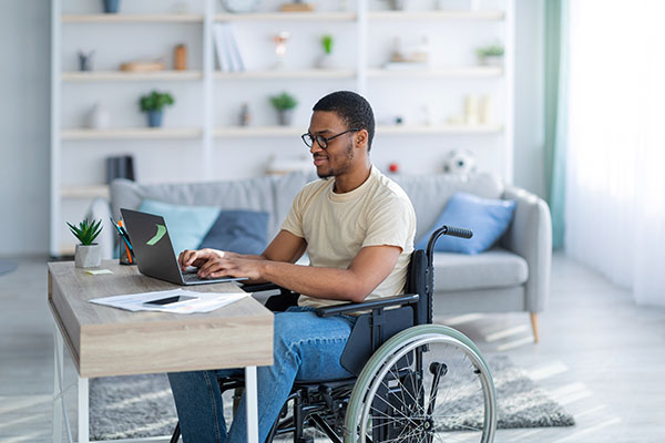 a male in a wheelchair at his laptop