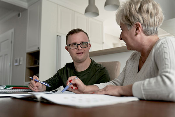 a man with down syndrome looking at papers with his mom