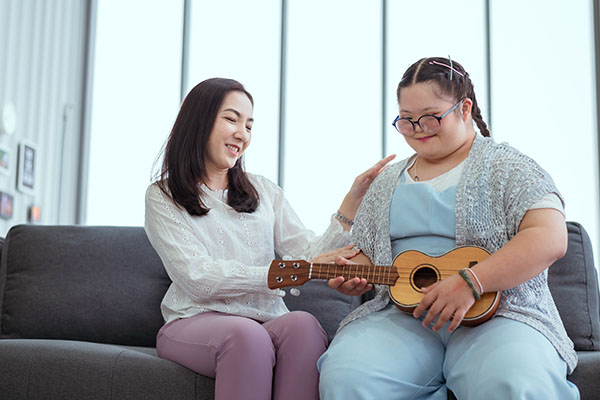 Autistic girl plays the guitar with her mom at her holiday home.