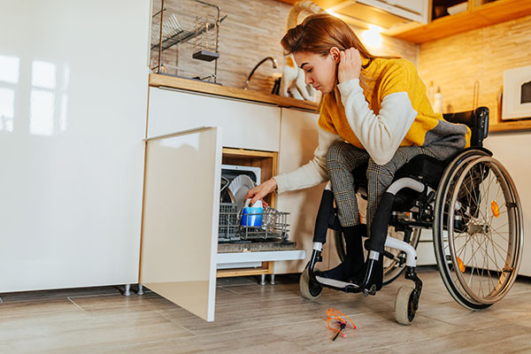 woman in a wheelchair loading dishwasher